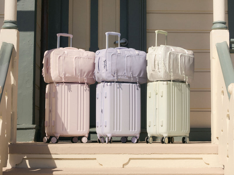 Set of CALPAK Ambeur Suitcases in light green Celadon, purple Sea Glass, and pink Shell Pink with Terra 26L Backpacks matching each suitcase color