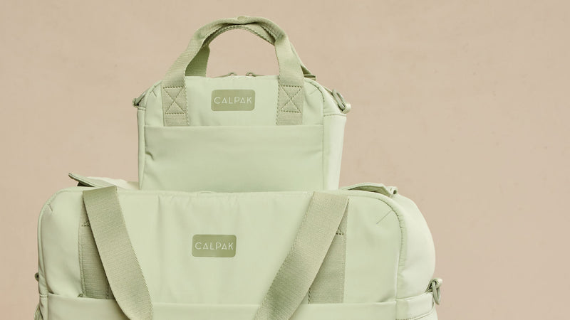 Two green CALPAK Connect Collection bags with 'Calpak' branding on a beige background