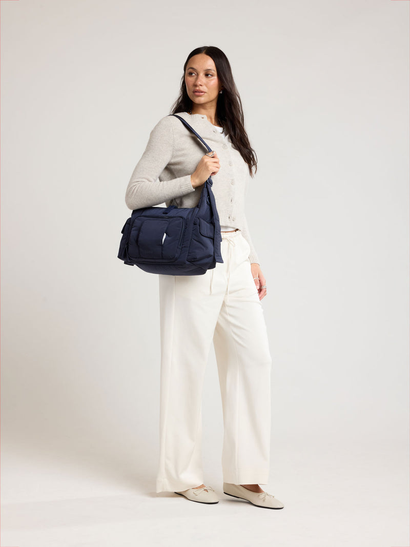 Woman wearing CALPAK Crossbody Diaper Bag in blue Navy