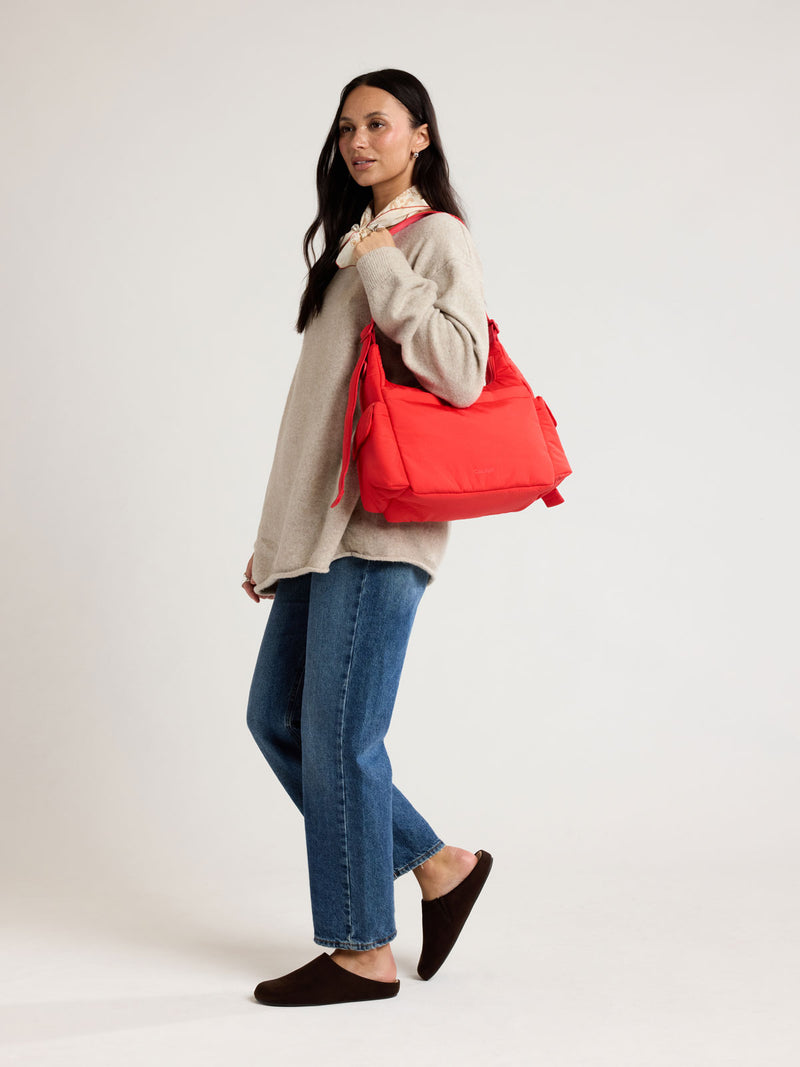 Woman wearing CALPAK Crossbody Diaper Bag in red Tomato