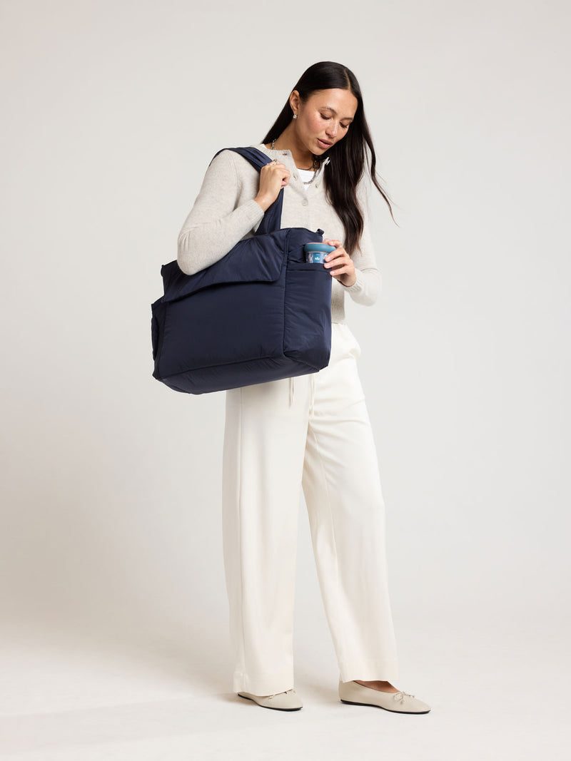 Woman wearing CALPAK Diaper Tote bag in blue Navy