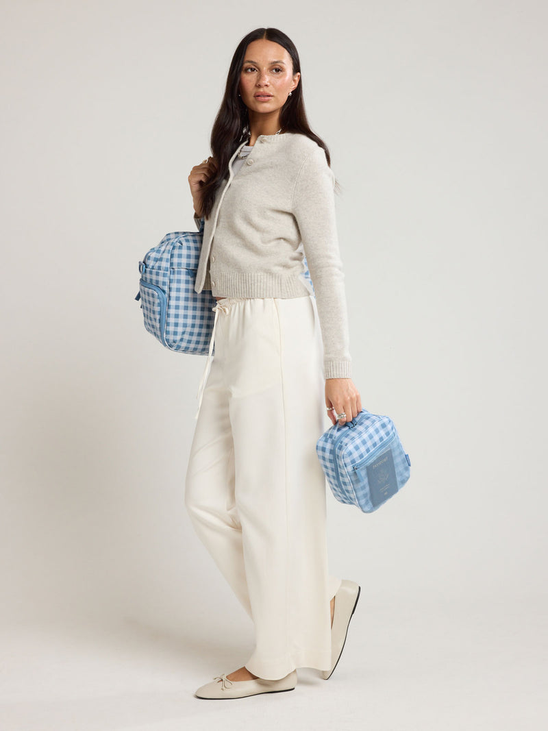 Woman holding the CALPAK Everything Cube in light blue and white gingham print