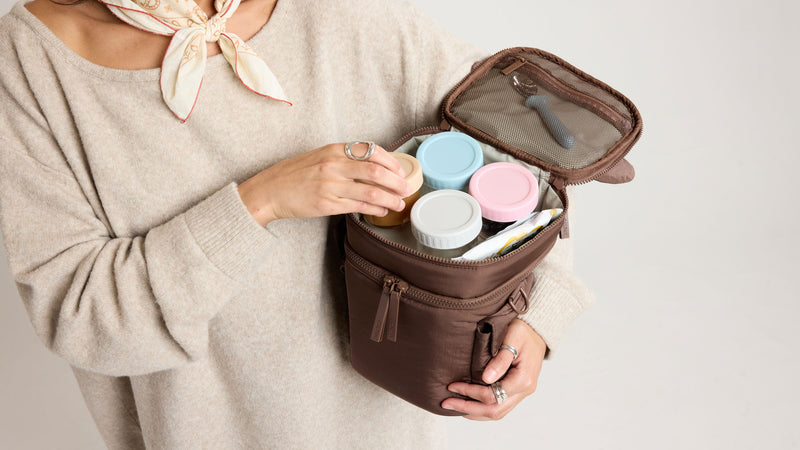 Person holding a brown Hazelnut CALPAK Insulated Baby Bottle Bag with baby bottles and mesh top
