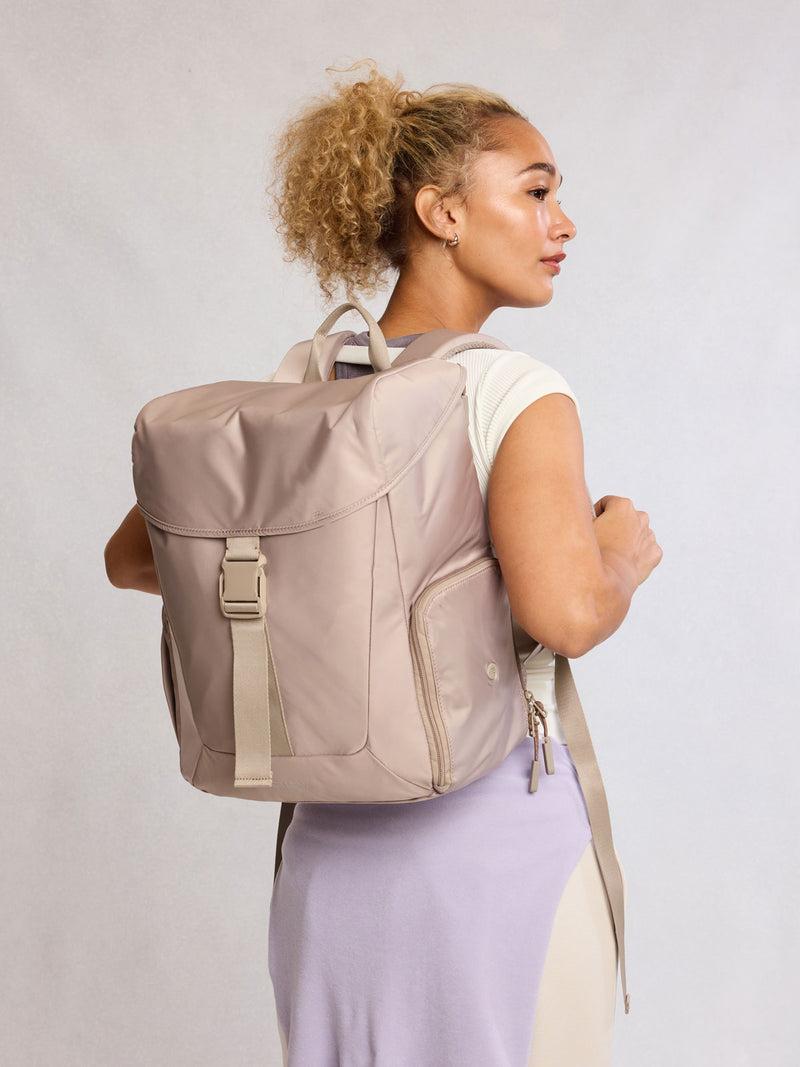Model wearing CALPAK Fit Gym Backpack in beige Greige front view with white background