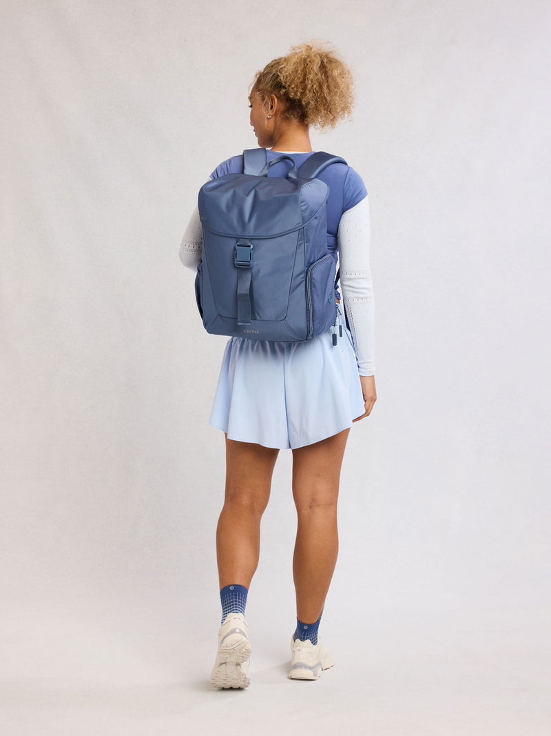 Model wearing CALPAK Fit Gym Backpack in blue Indigo front view with white background