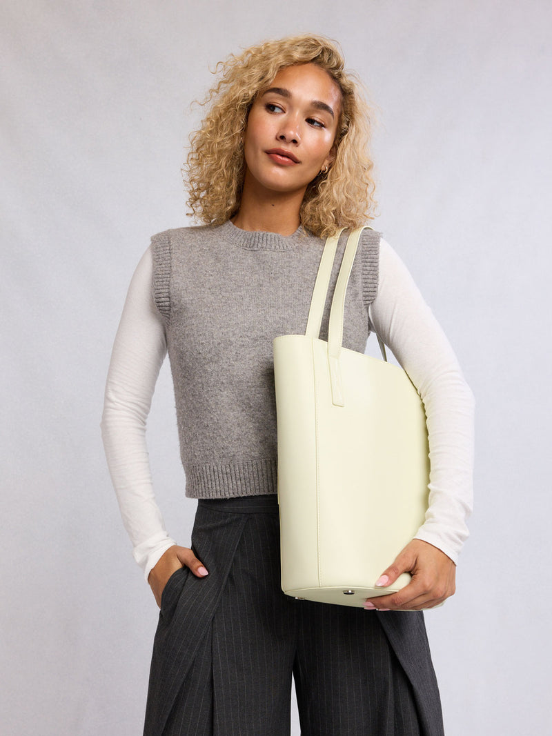 Woman wearing the CALPAK Haven 14" Haven Laptop Tote in light green Celadon