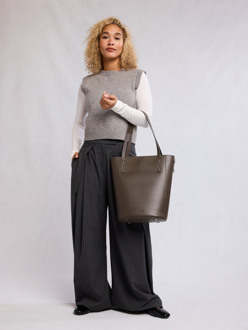 Woman holding the CALPAK Haven 14" Haven Laptop Tote in dark brown Mushroom
