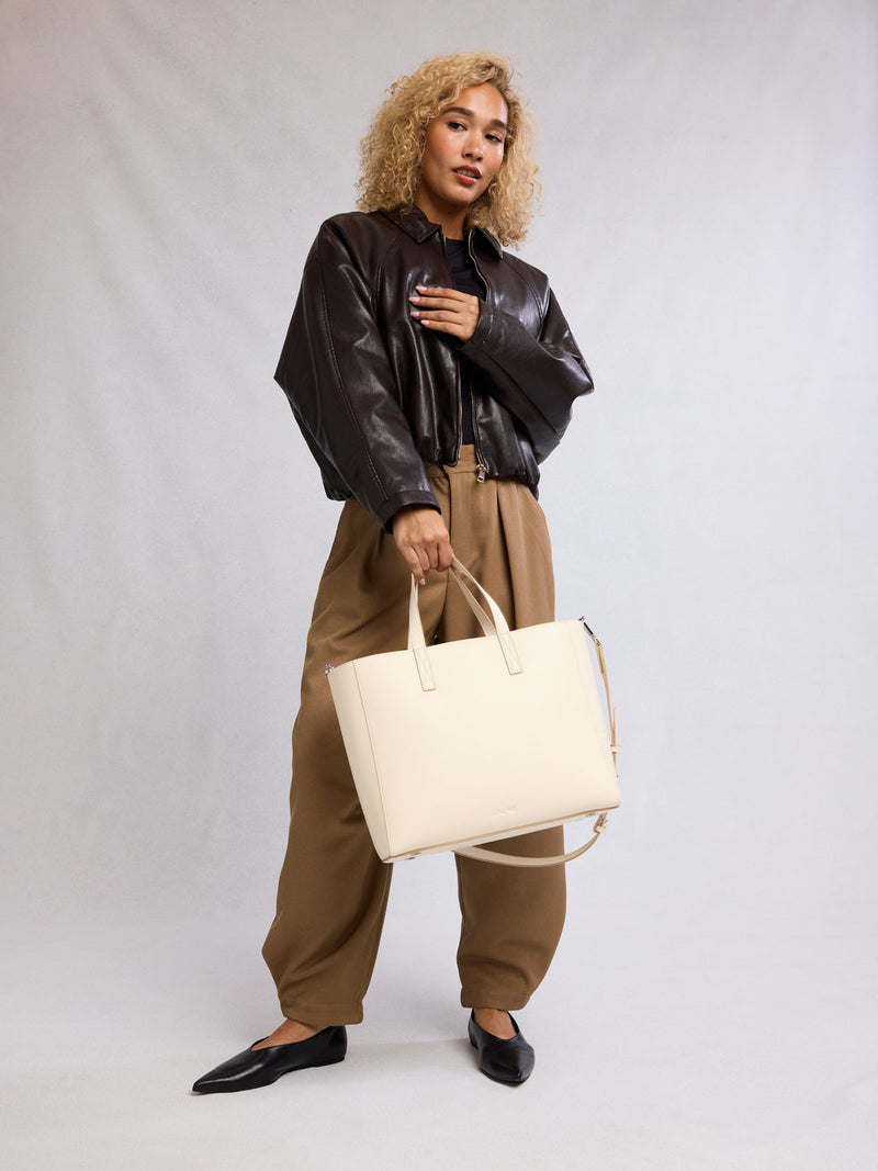 Person holding a CALPAK Haven 15" Laptop Tote in beige Buttercream