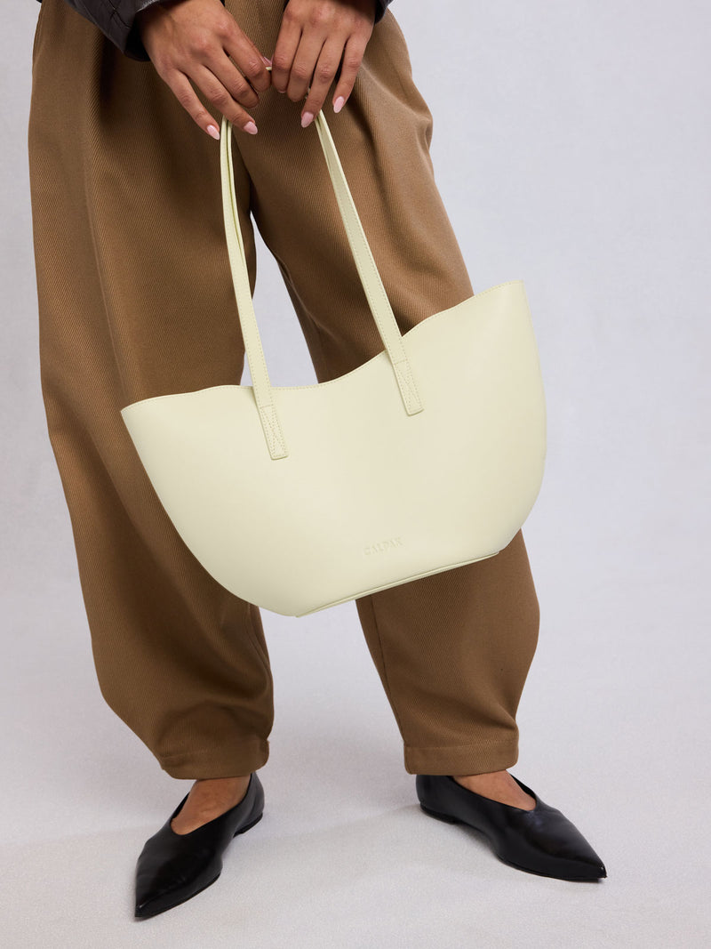 Person holding CALPAK Haven Tulip Tote in light green Celadon