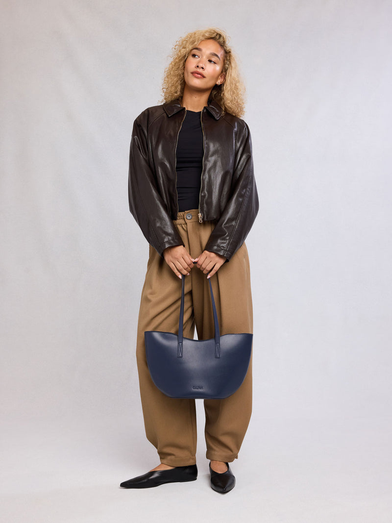 Woman holding CALPAK Haven Tulip Tote in dark blue