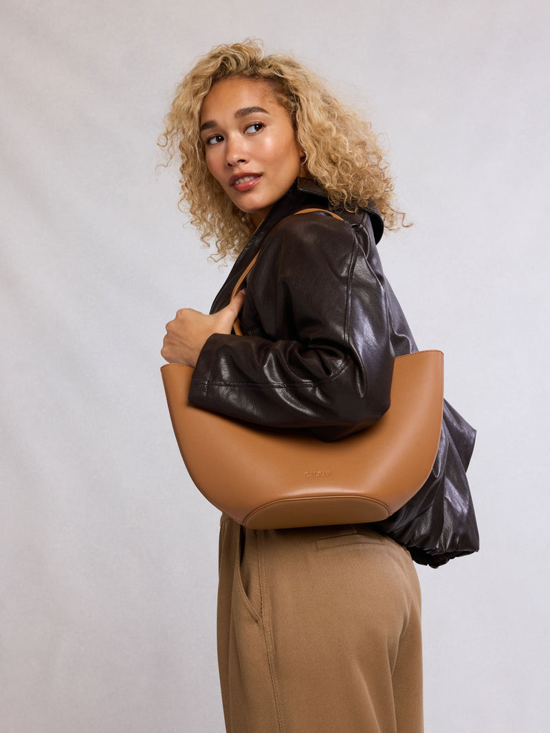 Woman holding CALPAK Haven Tulip Tote in light brown Toffee