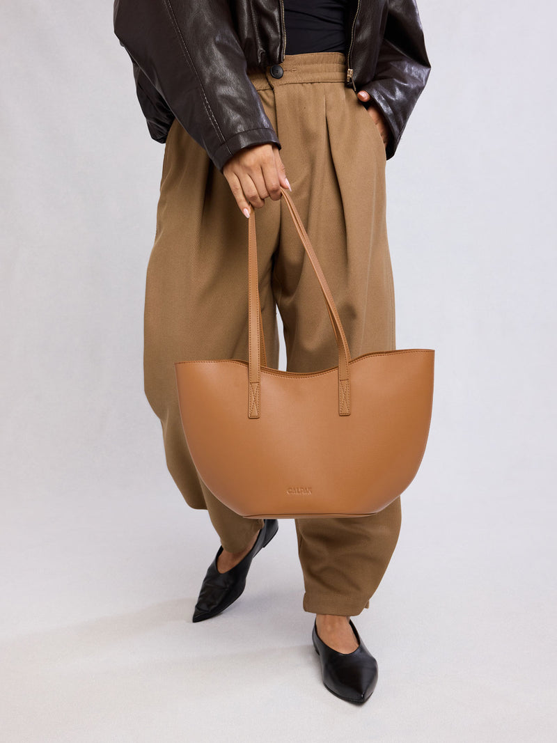 Person holding CALPAK Haven Tulip Tote in light brown Toffee