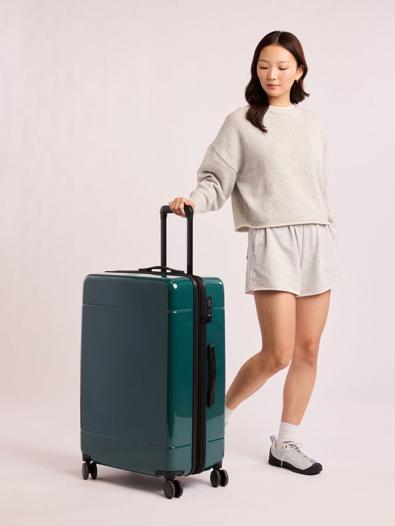 Woman with CALPAK Hue Large Luggage in dark green Kale