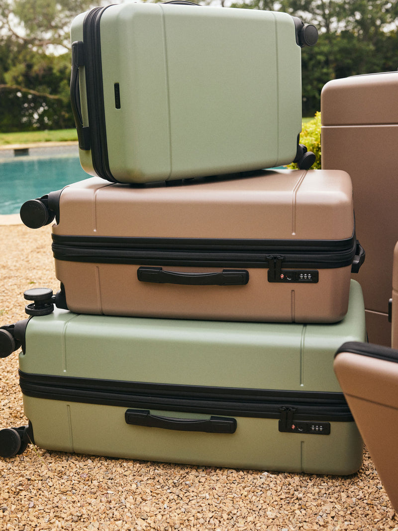 CALPAK Hue Medium Luggage in green Juniper and brown Chocolate stacked on top of each other