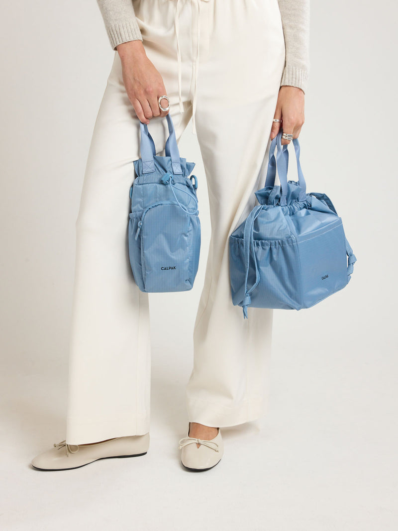 Person holding CALPAK Insulated Lunch Bag in blue French Blue