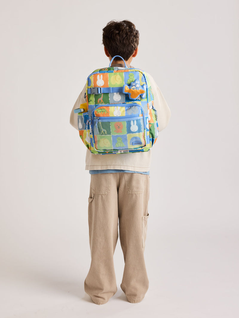 Child wearing the CALPAK Kids Large Backpack with Miffy and blue colorful animal pattern on a white background