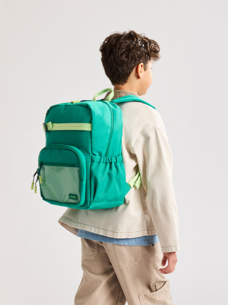 Child wearing a Green CALPAK Kids Medium Backpack with lime green accents on a white background