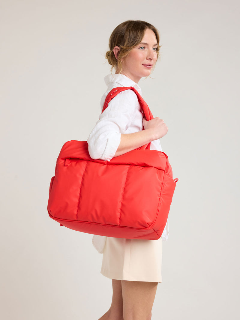 Person with CALPAK Luka Duffel in red Tomato