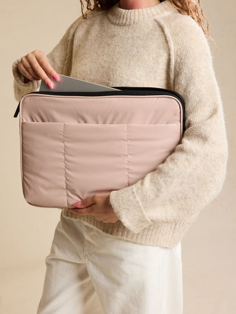 Model holding the CALPAK Luka 17-in Padded Laptop Sleeve in light pink Rose Quartz with puffy exterior back view