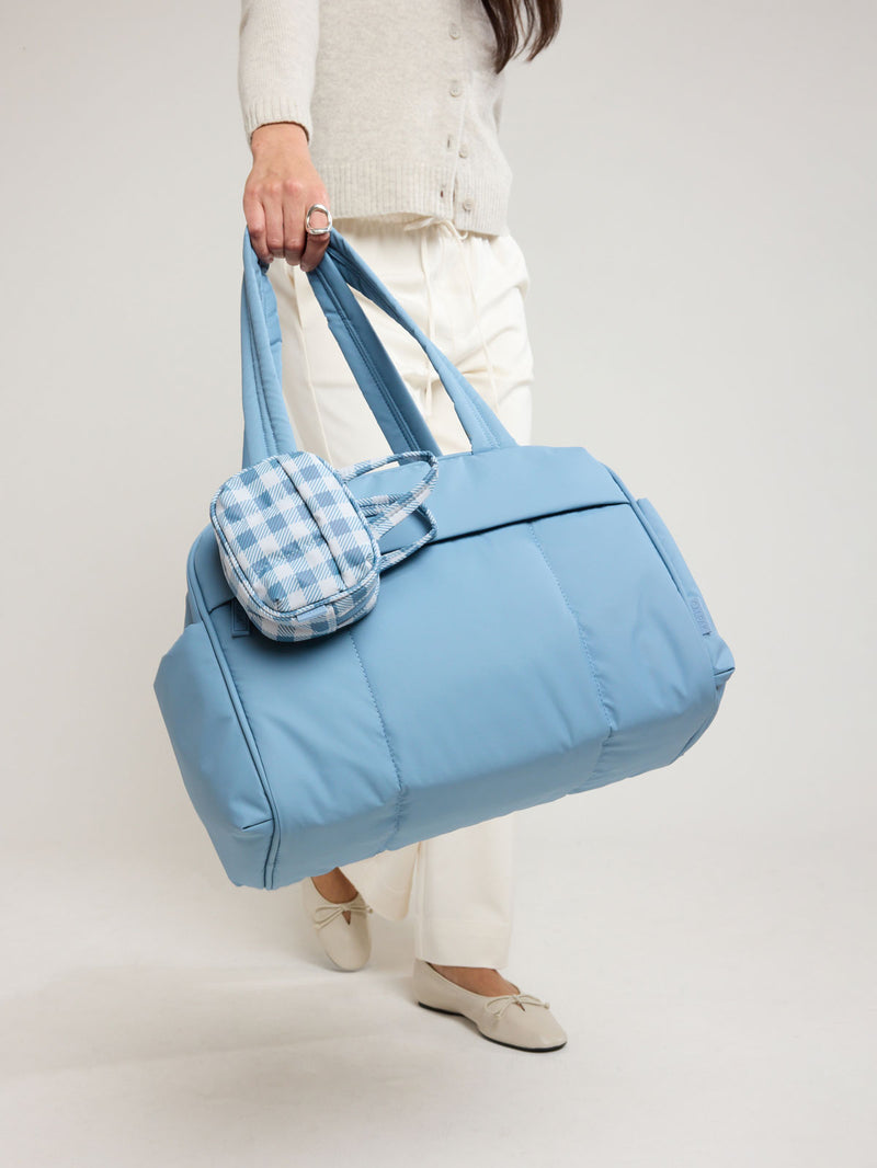 Model holding the CALPAK Luka Mini Duffel in light blue French Blue