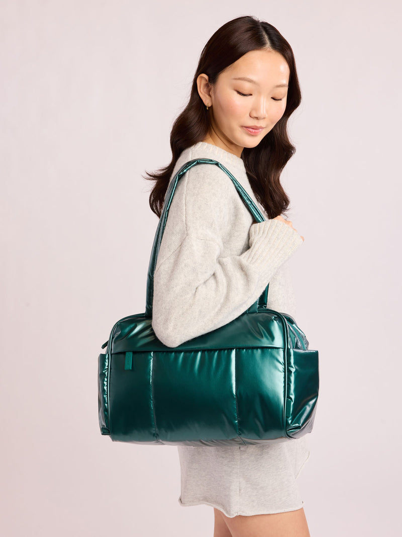 Woman wearing CALPAK Luka Mini Duffel in dark green shiny Glazed Kale