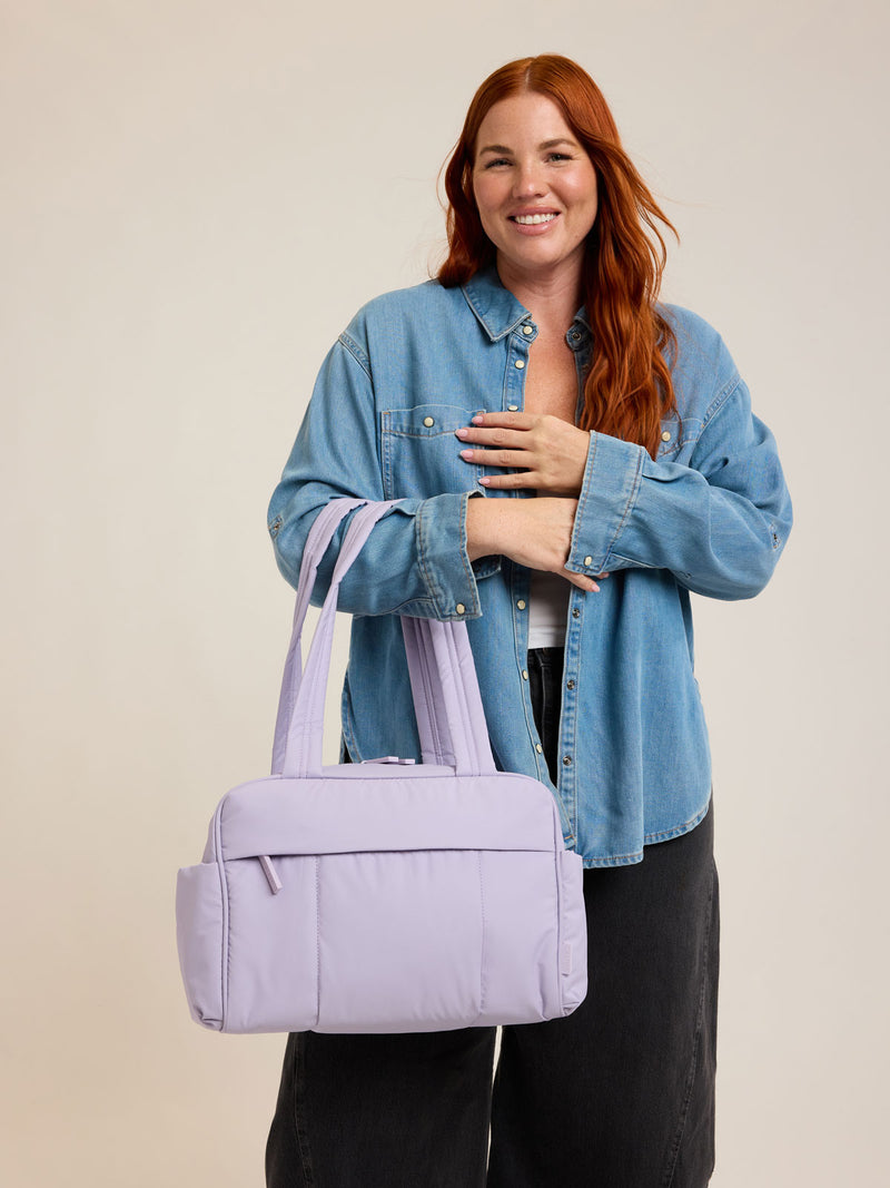 Model with CALPAK Luka Mini Duffel in light purple Orchid on a white background