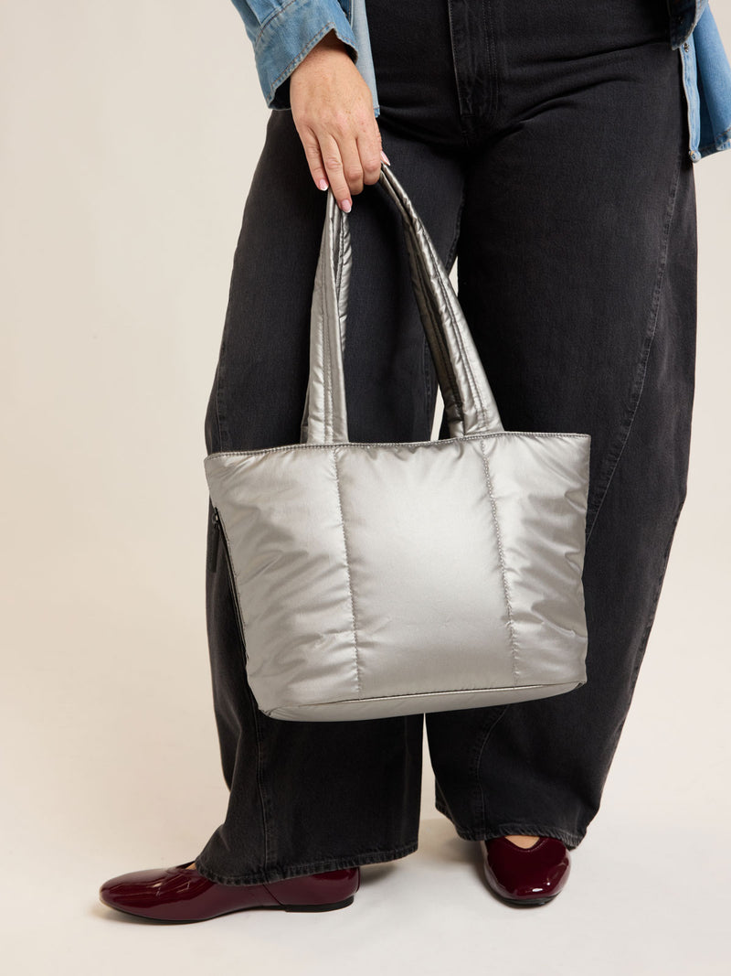 Model holding CALPAK Luka Mini Tote in metallic Gumetal grey a white background