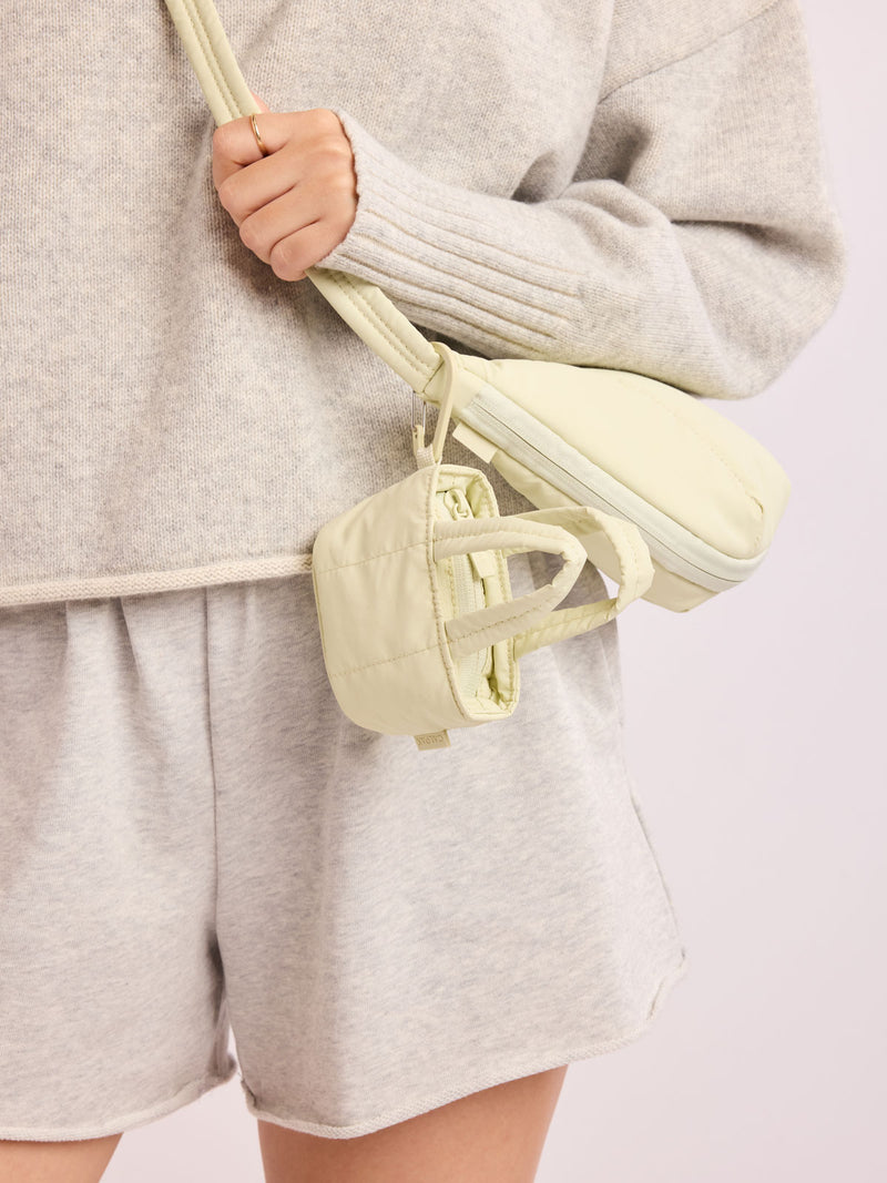 Model with bag that has CALPAK Luka Tote Zip Bag Charm in light green Celadon with carabiner attached