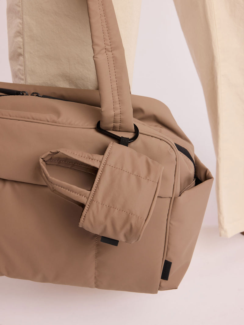Model with CALPAK Luka Tote Zip Bag Charm in light brown Chocolate with carabiner attached on a bag