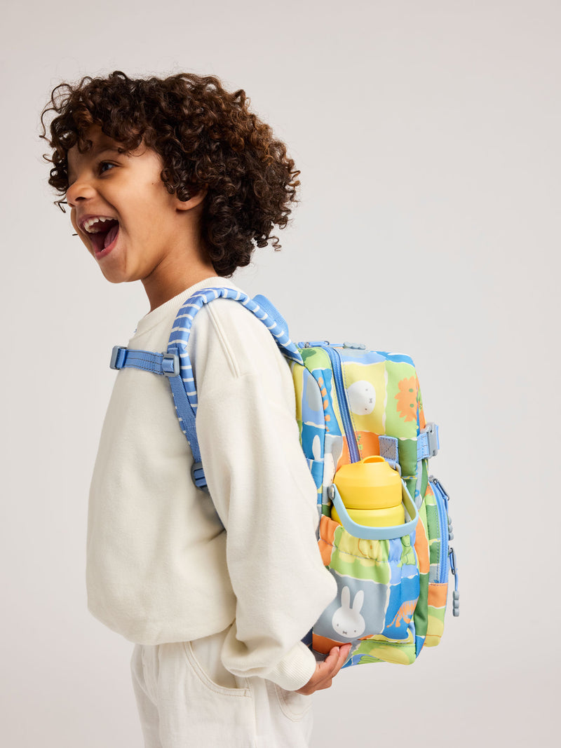 Child with a colorful CALPAK Kids Miffy backpack on a plain background