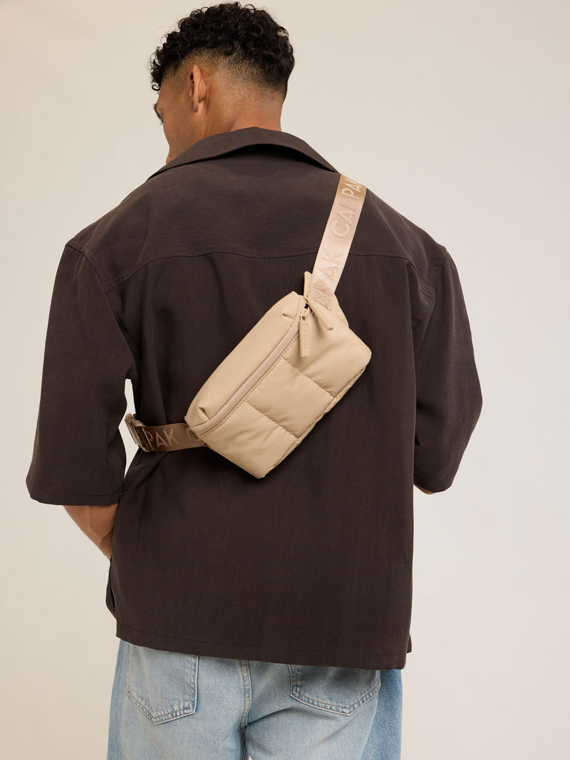Model wearing CALPAK Luka Mini Belt Bag in beige Latte on white background