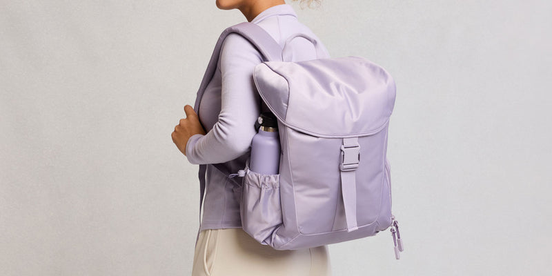 Person wearing a light purple CALPAK Fit Gym Backpack on a plain background