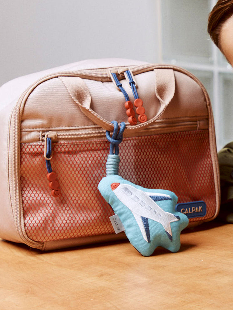 CALPAK Kids Pluffy Bag Charm white Airplane on blue plush attached to a Kids Lunch Bag in tan Khaki