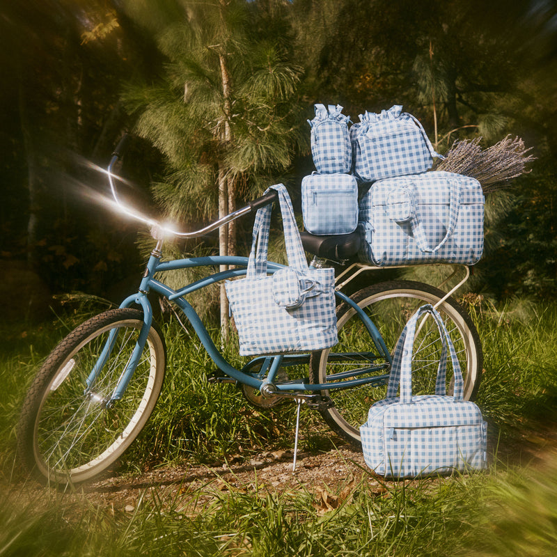 Bicycle with gingham-patterned CALPAK bags in a forest setting