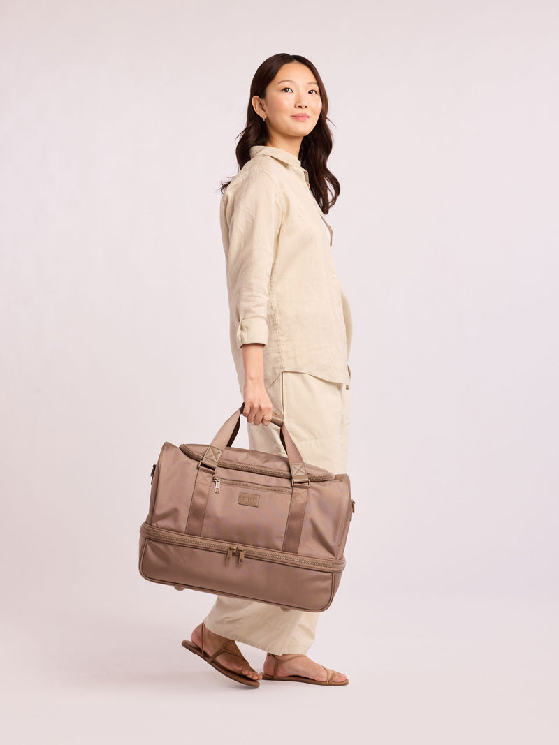 Woman with CALPAK Stevyn Duffel with Shoe Compartment in brown Chocolate