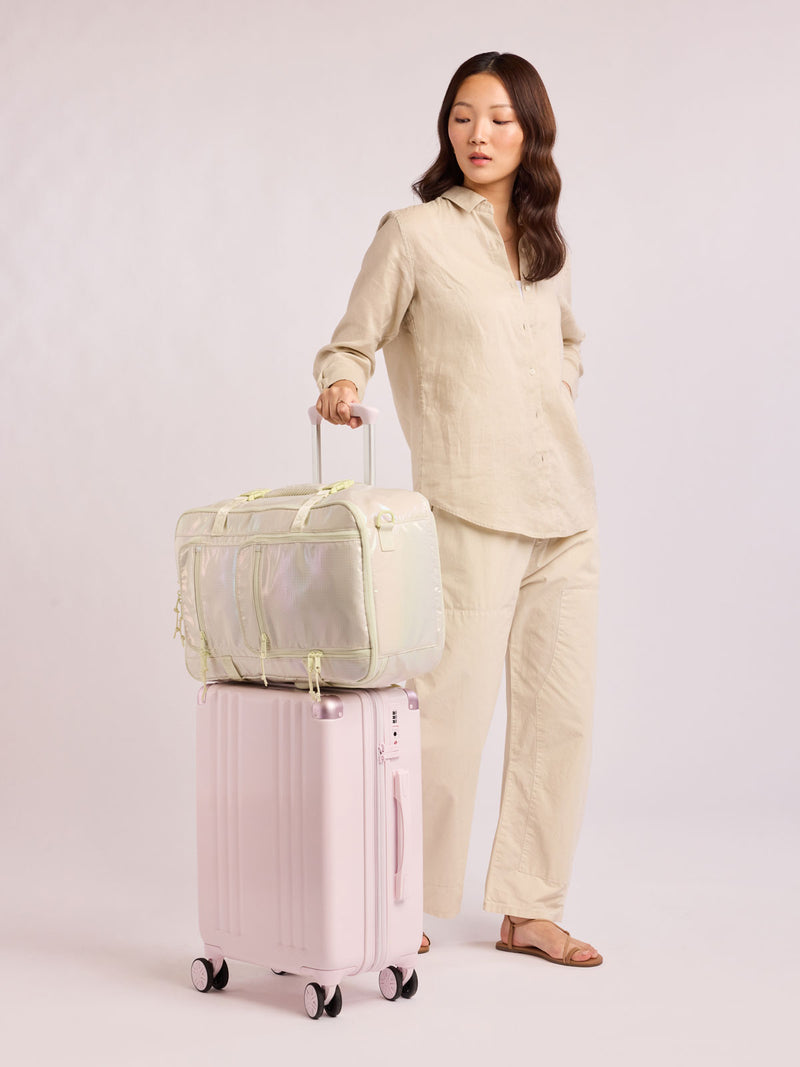 Model with CALPAK Terra 26L Laptop Duffel Backpack with multiple pockets in shiny white Moonbeam on a white background