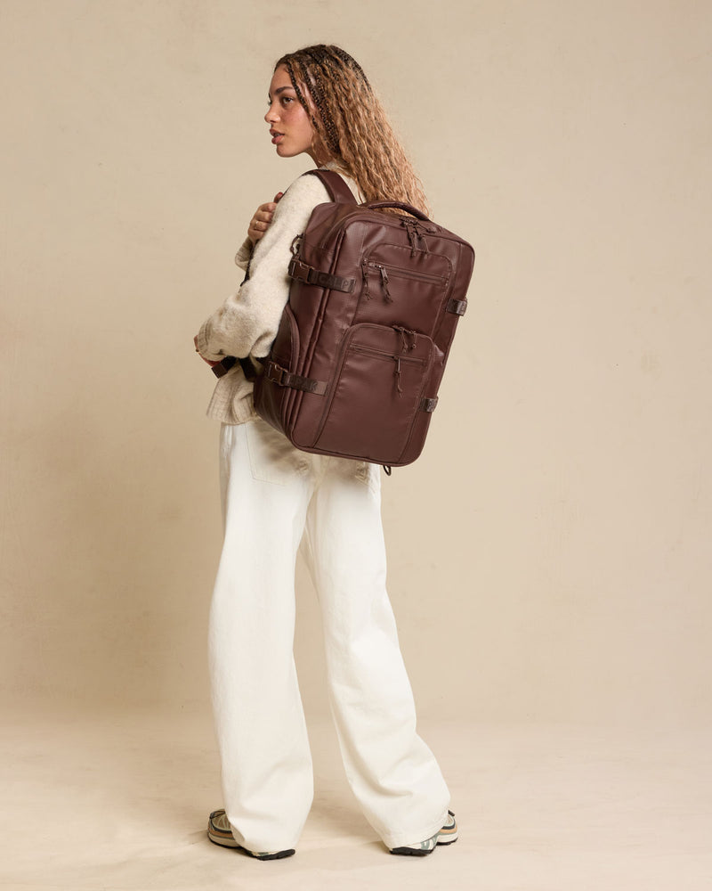 Woman wearing CALPAK Terra 26L Laptop Duffel Backpack in brown Walnut front view