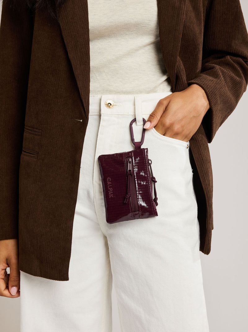 Person with the Dark red Dark Cherry CALPAK Terra Clippable Card Pouch with carabiner clipped on their pant buckle