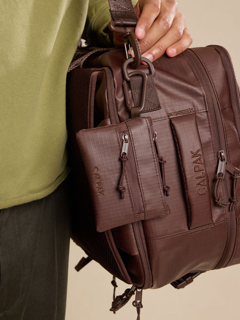 Model with CALPAK Terra Clippable Card Pouch in brown Walnut clipped to bag