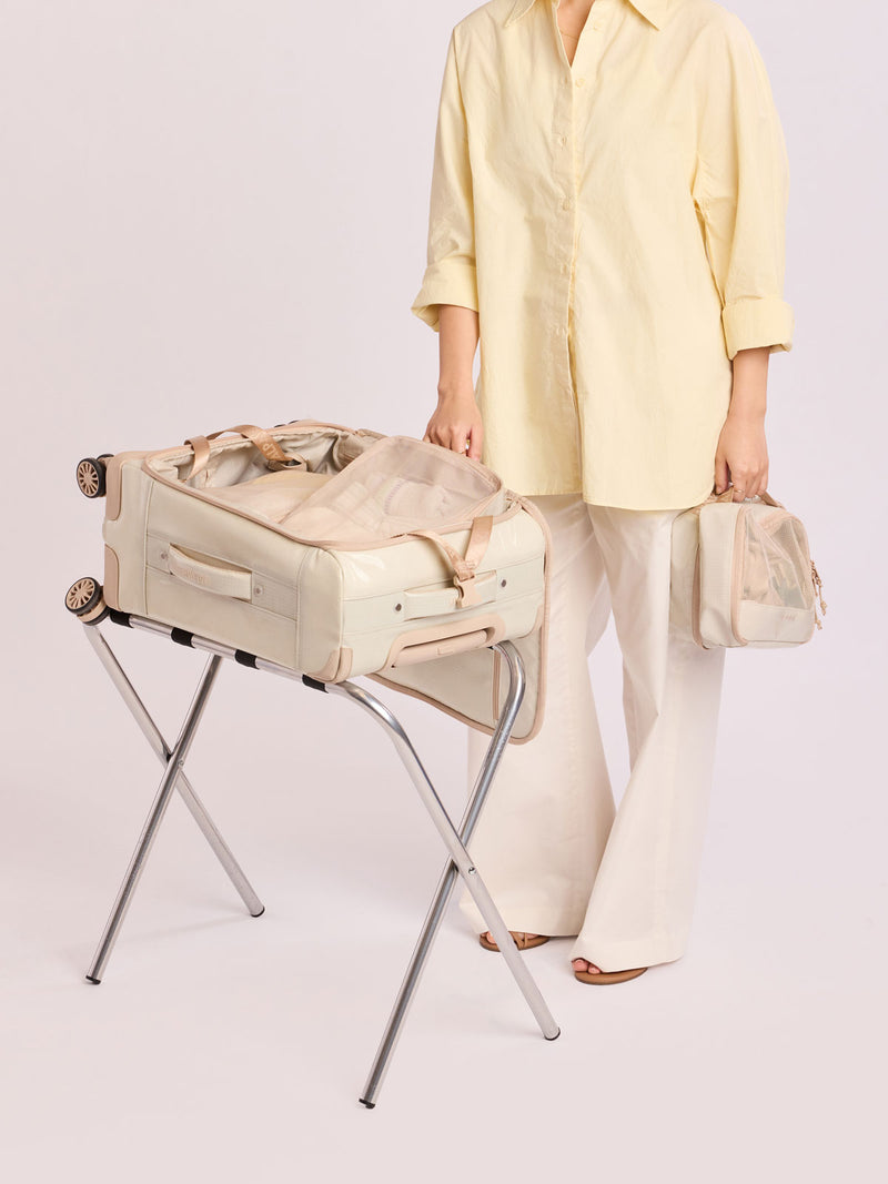 Model packing luggage with the CALPAK Terra 5-Piece Packing Cube Set in off-white beige White Sands with two small cubes, two medium cubes, and one large mesh cube with zippers and mesh