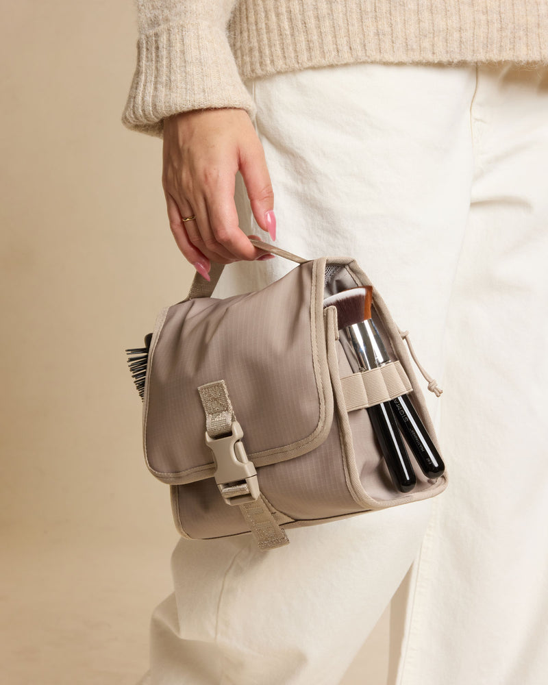 Model holding CALPAK Terra Hanging Toiletry Bag in beige Stone