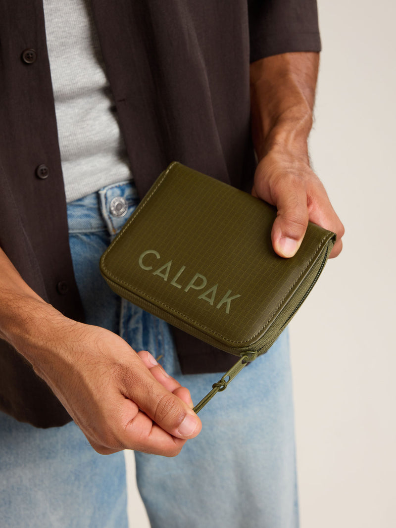 Model with CALPAK Terra Zip Passport Wallet in green Pine