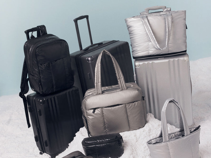 Collection of CALPAK suitcases and bags on a light blue background