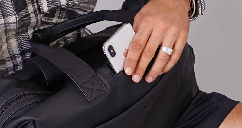 Model putting in phone in phone pocket of the Hue Duffel