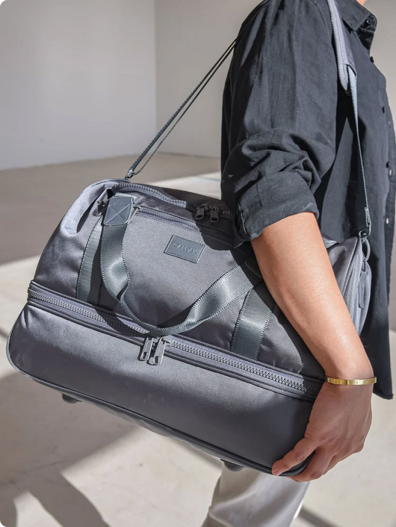 CALPAK Stevyn Duffel being worn by model in light blue 