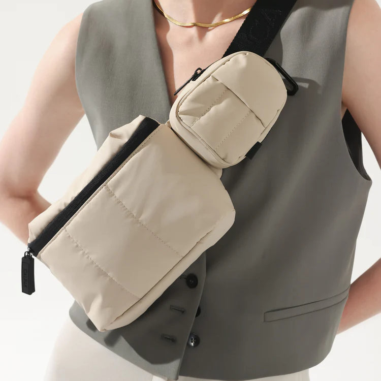 CALPAK Luka Belt Bag and Luka Backpack Key Pouch in white Oatmeal being worn by model