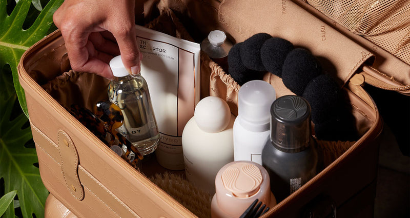 CALPAK Trnk Vanity Case being filled with toiletry items by model